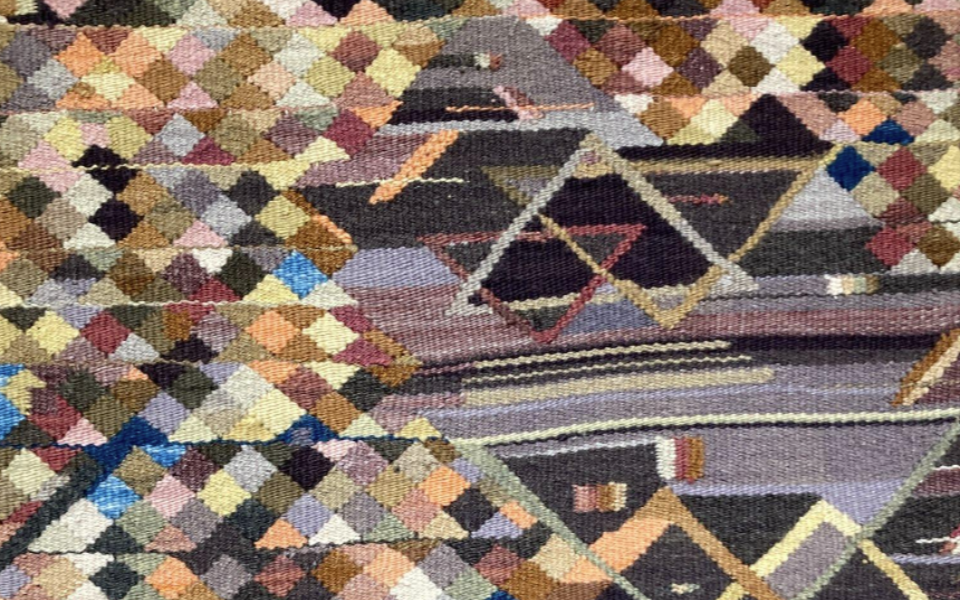 a rug-like object that has clashing designs on it, colored mostly brown, reds, oranges, and yellows