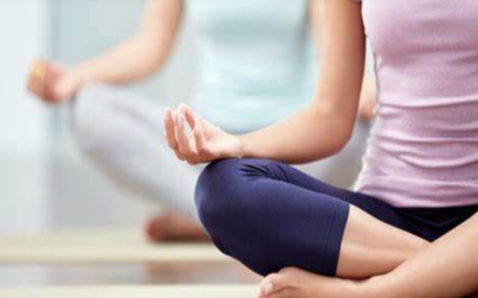 Two individuals sitting in yoga poses